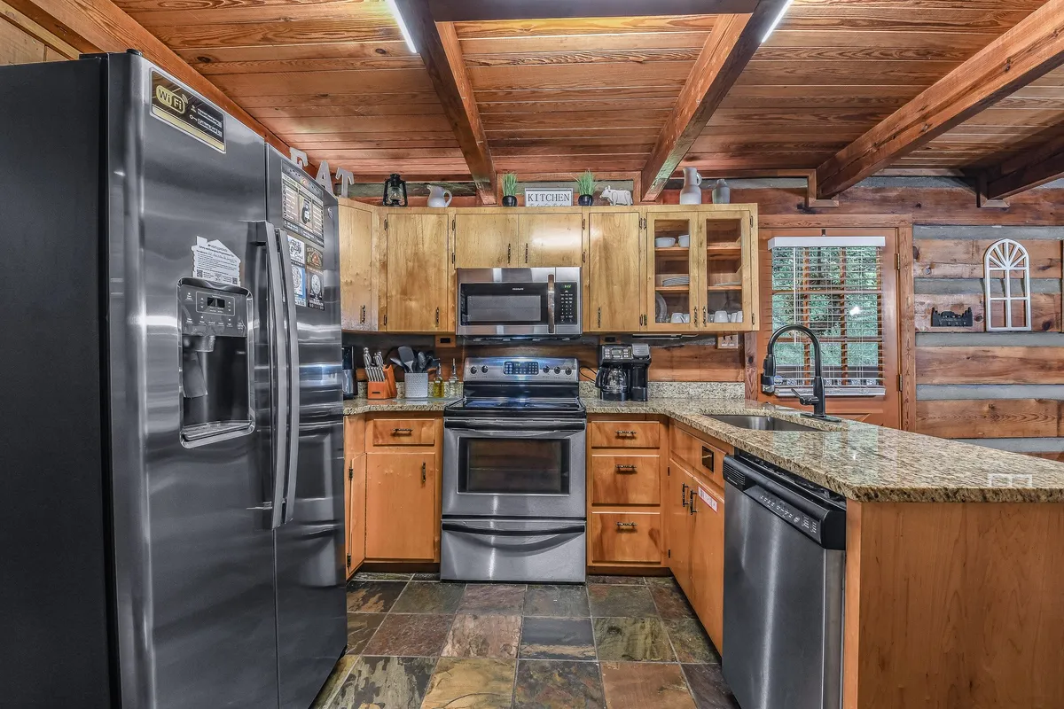 A well-equipped kitchen featuring gleaming stainless steel appliances, granite countertops, wooden cabinets, and slate flooring. The space feels open and inviting—ideal for cooking and gathering with family or friends.
