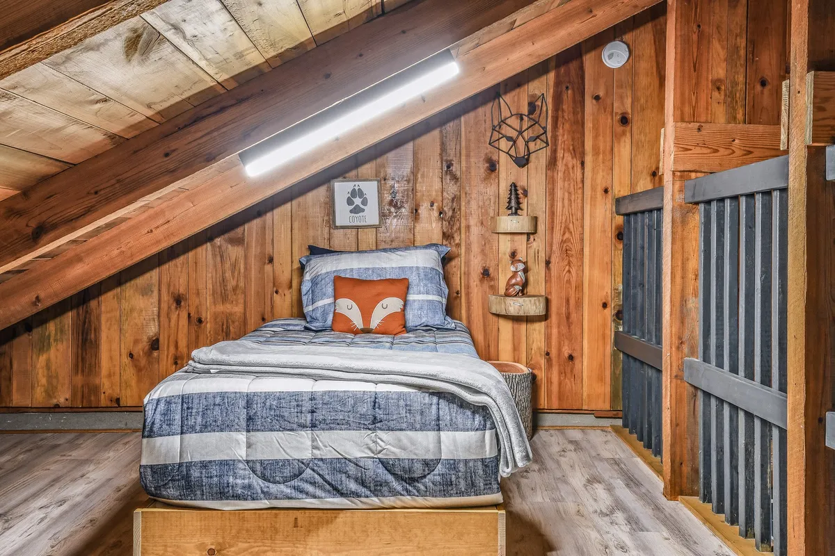 A playful bedroom featuring a bed with blue and white bedding, a whimsical fox-shaped pillow, wooden accent wall, and shelves with carefully arranged decorative items. The room feels inviting and imaginative, appealing to children and sparking a sense of adventure.
