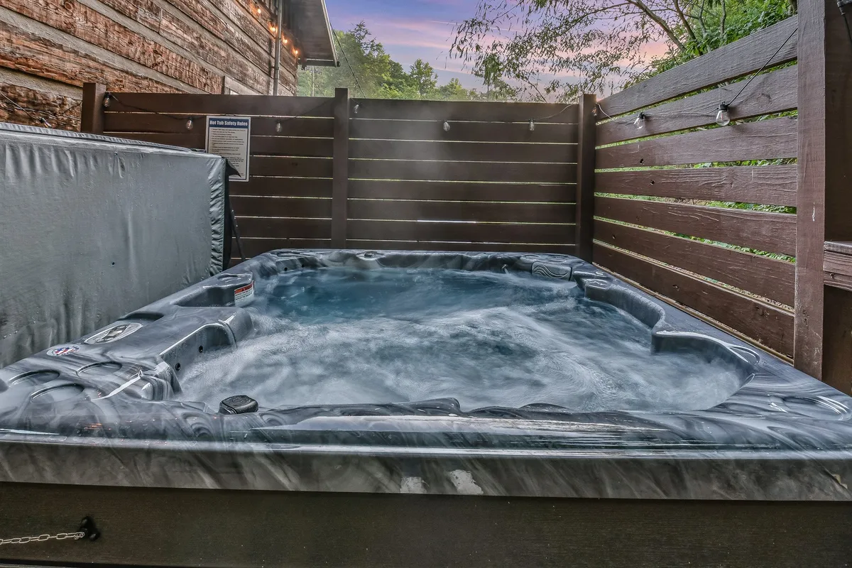 This photo showcases a private hot tub surrounded by a wooden fence and lush greenery, evoking tranquility and offering a perfect way for adults to unwind after a day of family activities. The secluded feel and natural elements tie into the outdoor adventure narrative.