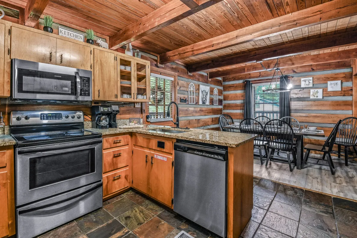 A view of the kitchen and adjacent dining area, both featuring matching wooden cabinetry, stainless steel appliances, and a granite countertop. The dining area is set for a cozy family meal, emphasizing togetherness and comfort.